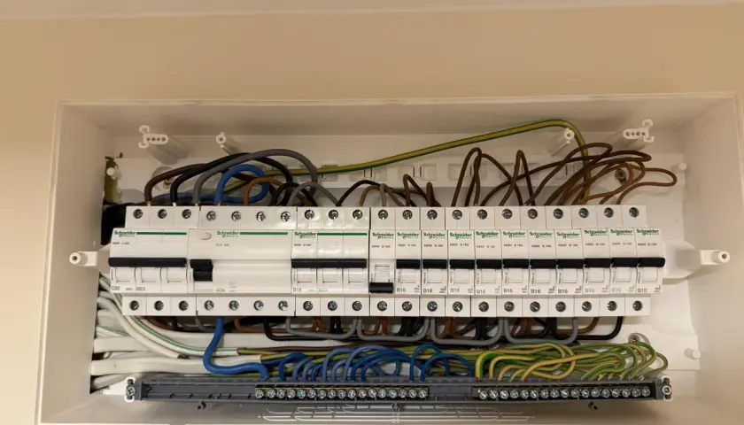 Widok otwartej skrzynki z bezpiecznikami i przewodami elektrycznymi.