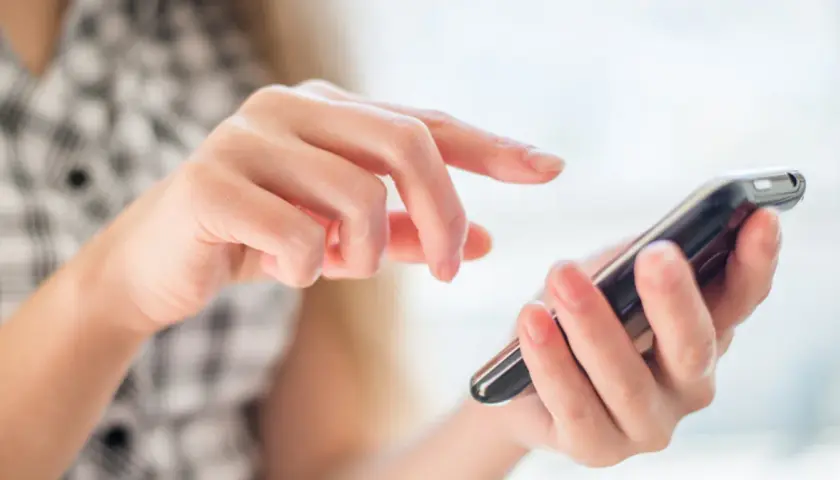 Dłonie obsługują smartfon, palce przesuwają się po ekranie, jakby wybierały opcję z menu +20 kierunkowego.