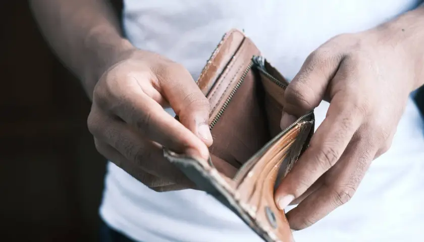 Mani che aprono un portafoglio vuoto, simbolo di problemi economici in famiglia.