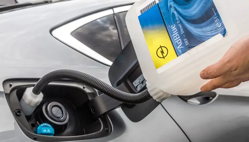 Rellenando el depósito de AdBlue de un coche. La etiqueta indica "AdBlue DEF - Diesel Exhaust Fluid". Saber cuanto dura el AdBlue es clave para evitar paradas.