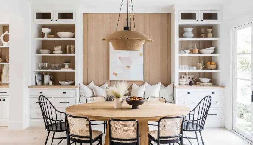 Chic dining table decor ideas: a round wood table with cane chairs, a woven pendant light, and built-in shelving.