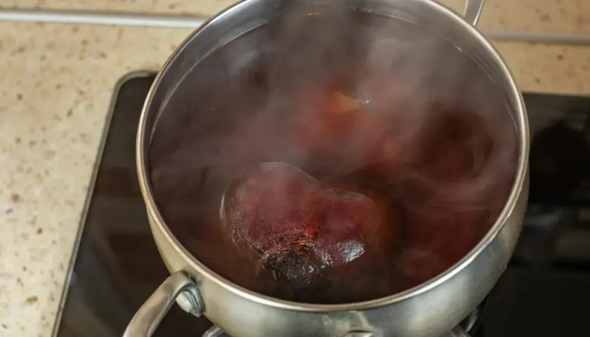 Cuisson de betteraves rouges dans une casserole d'eau bouillante. La vapeur s'échappe de la cocotte.