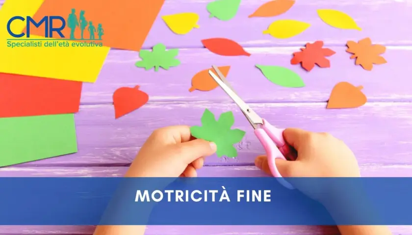 Mani di bambino che ritagliano forme di foglie colorate con forbici rosa, un'attività per sviluppare la motricità fine.
