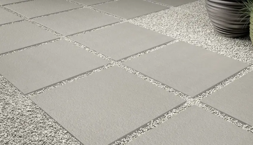 Posa a secco su ghiaia: lastre quadrate grigie alternate a ghiaia bianca, creando un percorso moderno e pulito.