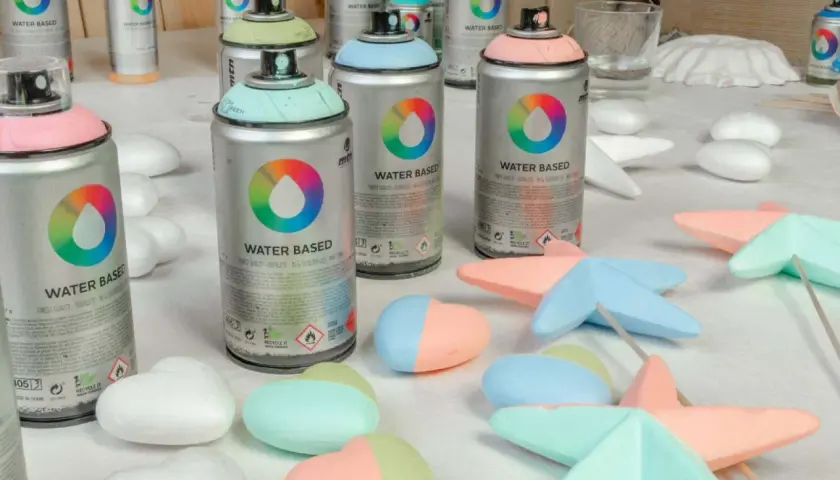 Latas de spray de pintar espuma poliuretano en tonos pastel, listas para dar color a figuras de poliestireno.