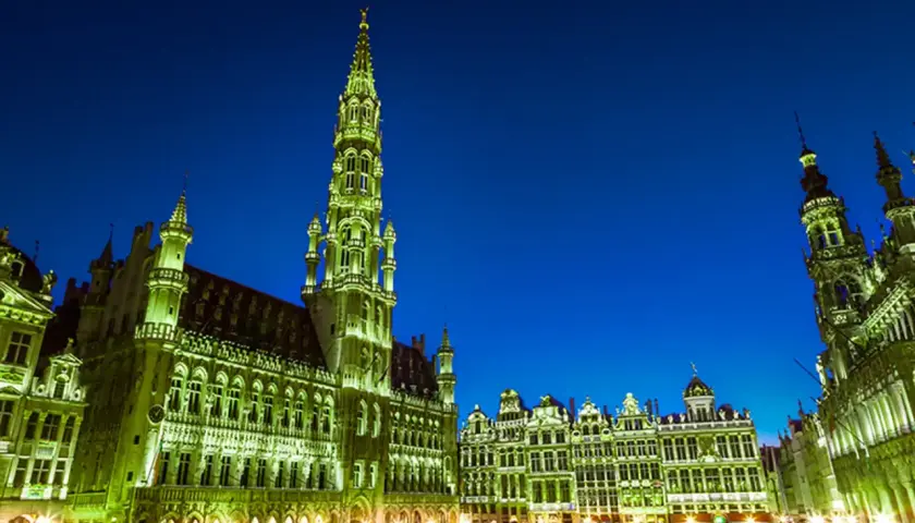 Wieczorem na Grand Place w Brukseli, oświetlone ratusz i kamienice tworzą magiczny widok.