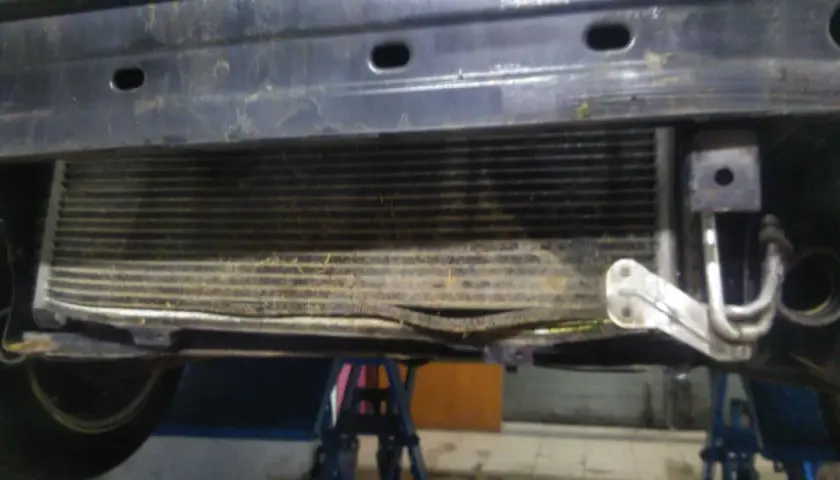 Uszkodzony skraplacz klimatyzacji objawy: zgięte żeberka, widoczne uszkodzenia mechaniczne.
