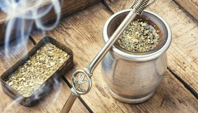Gorąca yerba mate, parująca z metalowego naczynia, obok pojemnika z suszem. Czas na odkrycie jej wyjątkowego smaku.