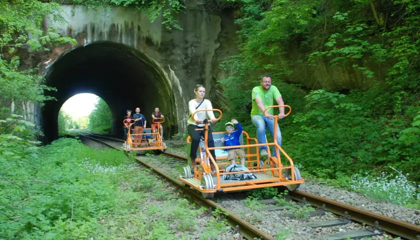 Rodzina na drezynach w Bieszczadach, przejeżdża obok tunelu kolejowego.