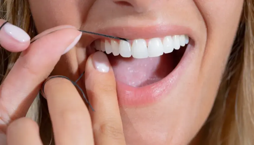 Dita curate usano filo interdentale abrasivo per pulire i denti bianchi e brillanti.