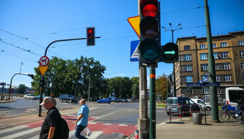 Sygnalizator S2 z zieloną strzałką w prawo, czerwonym światłem u góry. Ludzie przechodzą przez pasy.