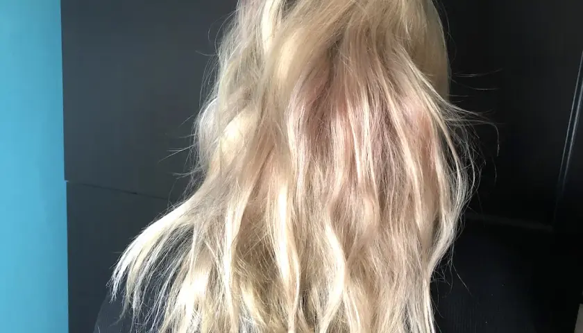 En person med blont, vågigt hår med inslag av rosa nyanser. En ny hårfärg som ger en unik look.