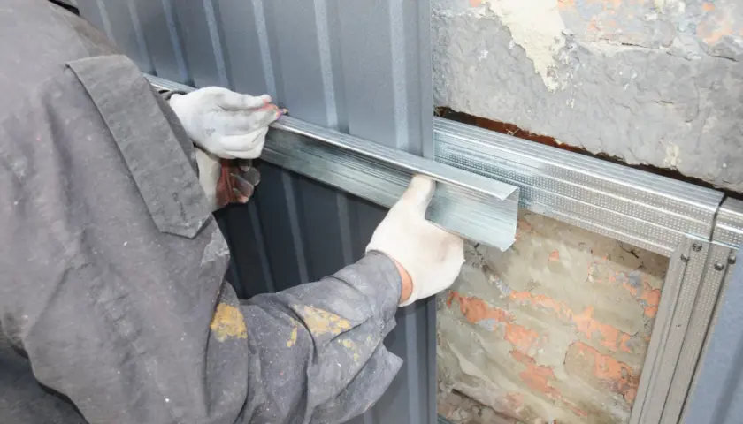 Arbeiter montiert Metallprofile für die Abdichtung des Hauses.