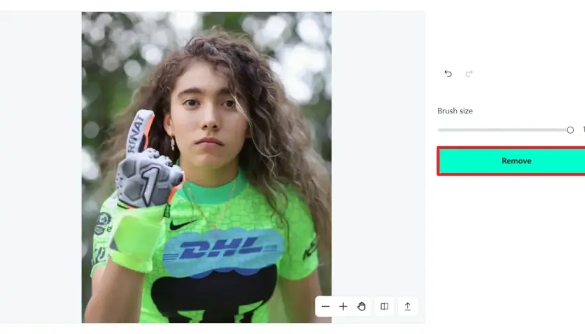 Jeune gardienne de but avec un gant, prête à enlever logo sur son maillot vert fluo.