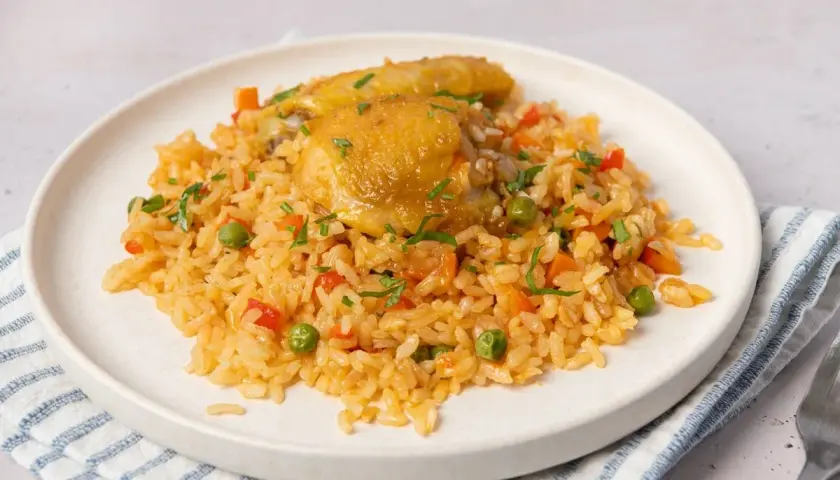 Plato de arroz con pollo, zanahorias, guisantes y pimientos rojos. Una deliciosa receta de arroz con pollo lista para servir.