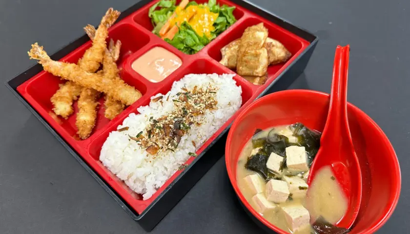 A delicious shrimp bento box with crispy fried shrimp, rice, salad, and tofu, served with miso soup.