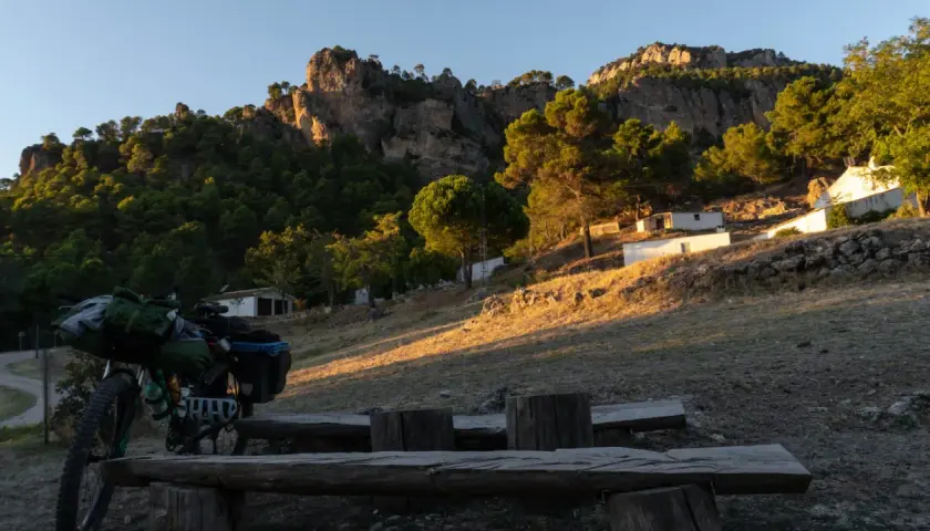 Bicicleta cargada para aventura, lista para explorar el GR 247 en bici. Paisaje montañoso al atardecer.
