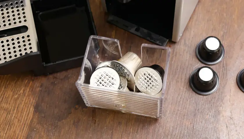 Pojemnik z kapsułkami do Nespresso, obok ekspresu i tacki na zużyte kapsułki. Czas na odkamienianie!