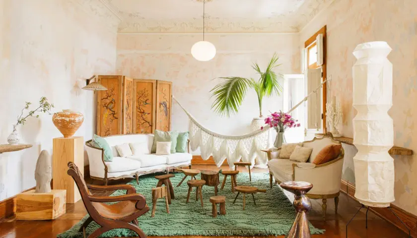 A serene boho space with a white sofa, macrame hammock, and eclectic decor.