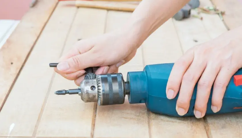 Manos ajustando el portabrocas de un taladro para cambiar la broca.