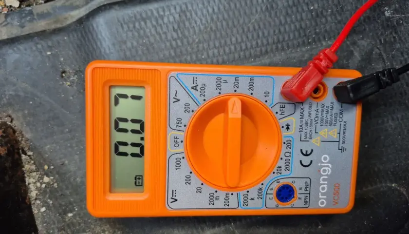 Pomarańczowy multimetr z wyświetlaczem pokazującym 0.00 i podłączonymi przewodami.