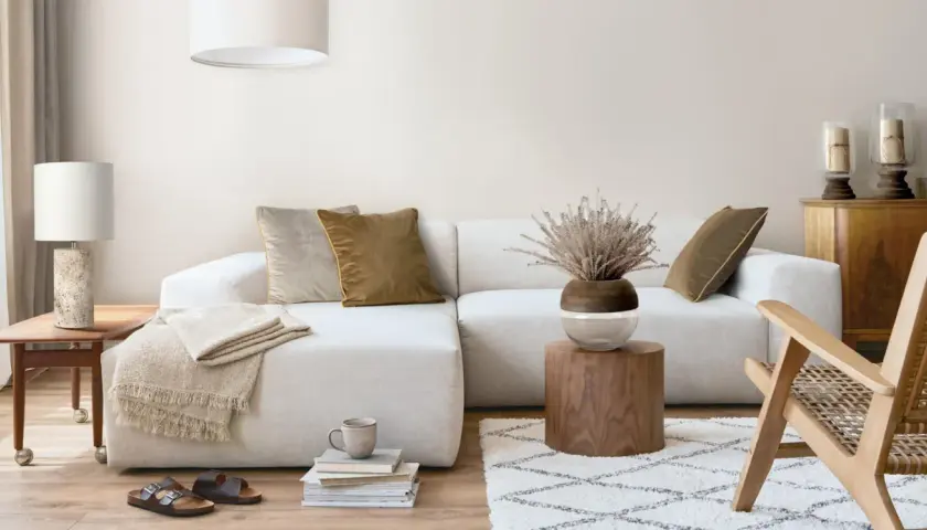 Przytulny salon boho z jasną sofą, drewnianymi meblami i naturalnymi dodatkami.
