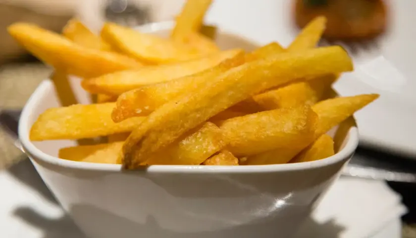 Chrupiące złote frytki w białej misce.