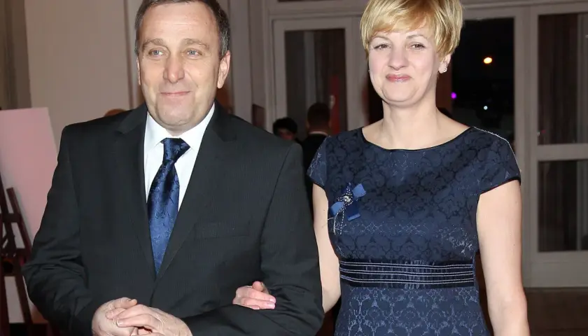 Cezary Grabarczyk z żoną, w eleganckich strojach. Może rozmawiają o swoich dzieciach i ich przyszłości.
