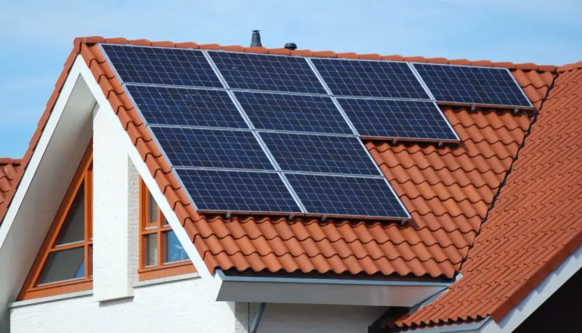 Moderne Solaranlagen auf dem roten Ziegeldach eines Hauses, bereit, Sonnenenergie zu sammeln.