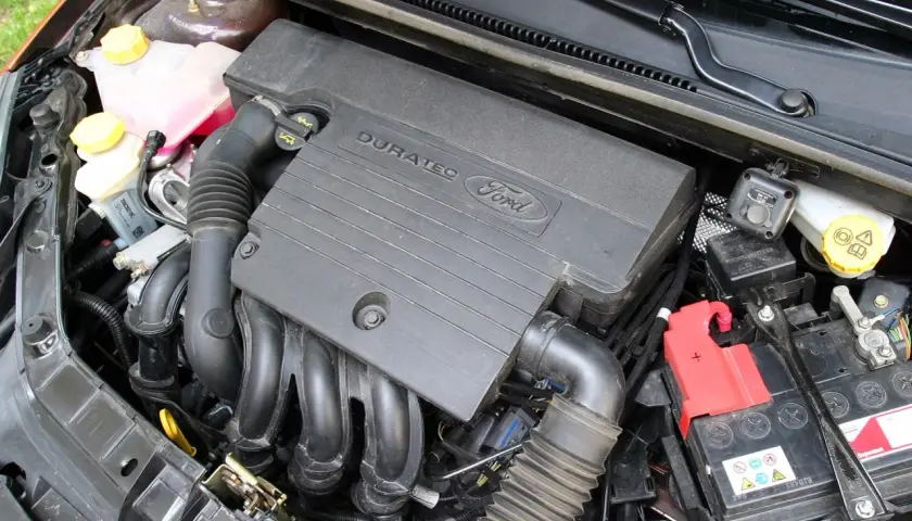 Silnik Duratec w Fordzie Fiesta Mk6. Widoczny jest czarny plastikowy kolektor, przewody i akumulator.