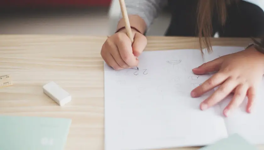 Niño de 12 años practicando caligrafía en un cuaderno. Un lápiz, goma y regla sugieren cómo mejorar la letra de un niño de 12 años.