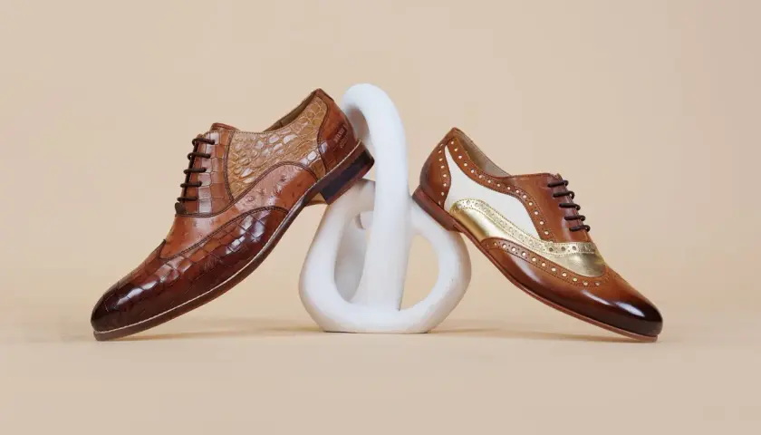 Comment porter des richelieu femme : deux paires de chaussures élégantes en cuir marron, ornées de textures et de détails dorés, posées sur un socle blanc.