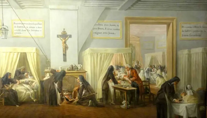L'hôpital qui se fout de la charité : des religieuses soignent des malades, mais l'une d'elles semble négliger un patient. Une scène ironique.