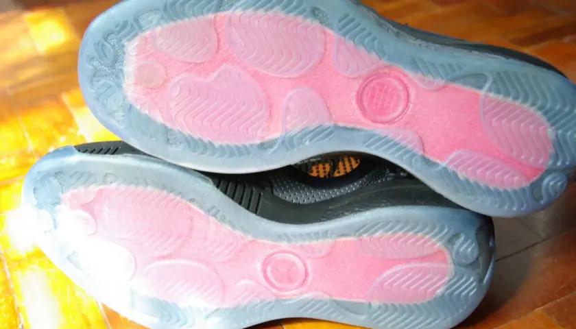 Soles of two black sneakers with pink grip zones and clear rubber outsoles. These shoes are designed to maximize traction, offering a great solution for how to make shoes more grippy.
