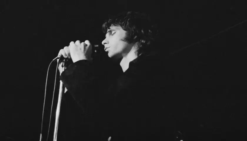 Jim Morrison z The Doors śpiewa do mikrofonu, zamykając oczy.