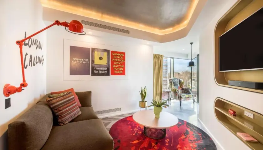 Nowoczesny pokój hotelowy w Londynie z kanapą, stolikiem i plakatem "London Calling".