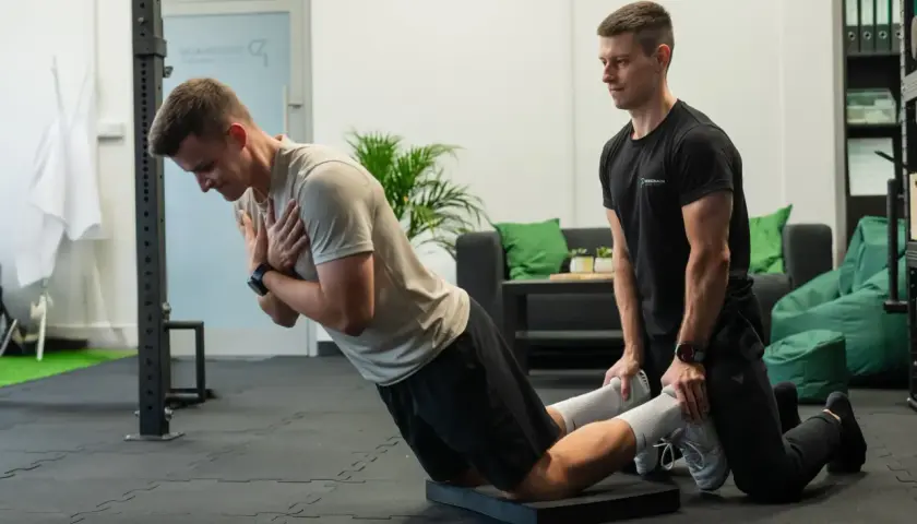 Trener pomaga w ćwiczeniu na maszynie do ćwiczeń, wspierając funkcjonalny trening siłowy.