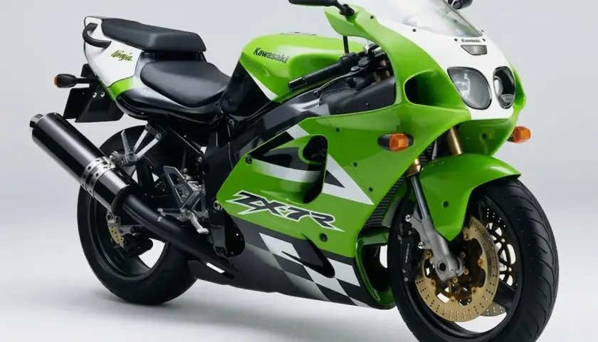 La parte posterior de una moto Kawasaki Ninja verde y blanca, con detalles de cuadros de ajedrez y un escape negro.