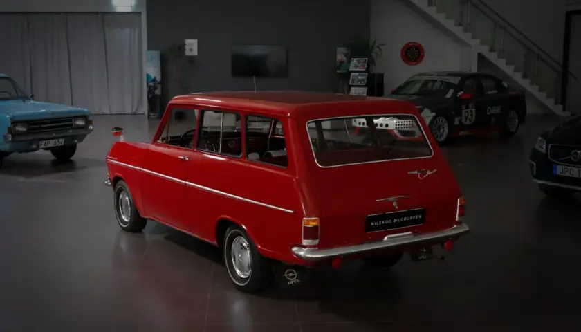 Röd Opel Kadett Caravan, en klassiker som kan vara en skattebefriad bil. Bredvid står en blå bil och en racingbil.