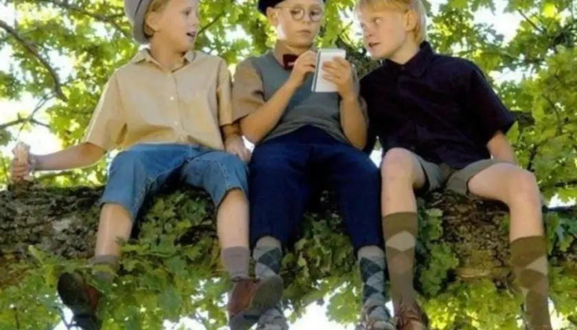 Tre pojkar sitter i ett träd, en håller en glass. En scen från svenska barnfilmer 2000-talet.