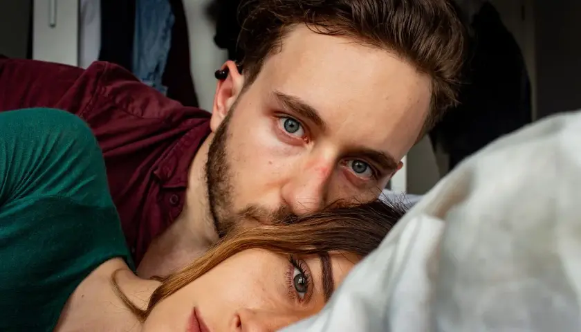 Bliskość i intymność. Psychologia zwracania się po imieniu buduje więź. Para leży blisko siebie, patrząc w obiektyw.