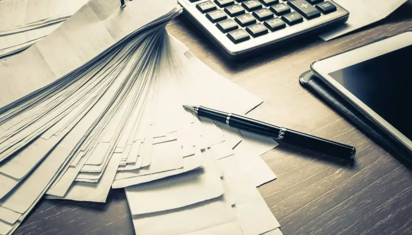 Stos dokumentów, kalkulator i długopis na biurku. Może to być biuro Svea Ekonomi na Cyprze, gdzie analizuje się finanse.
