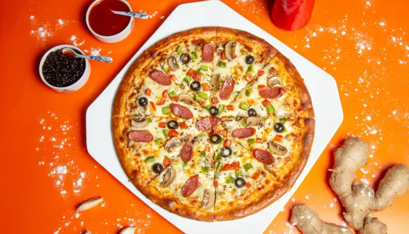 Apetyczna pizza z kiełbasą, pieczarkami i papryką. Widać też sosy i imbir, sugerujące ciekawe pizza składniki.
