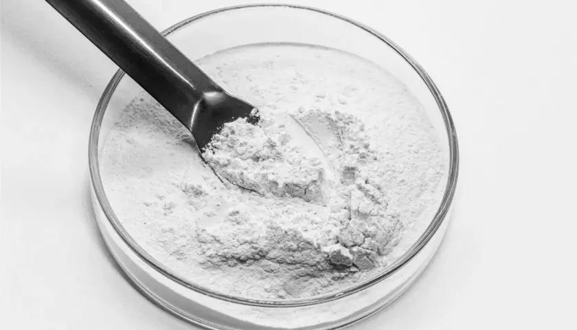 Biały proszek, prawdopodobnie kwas salicylowy jak stosować, w szklanej miseczce laboratoryjnej, nabierany metalową szpatułką.