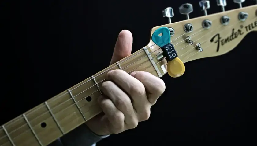 Dłoń grająca akord na gryfie gitary Fender Telecaster. Kostka z uchwytem na gryfie.