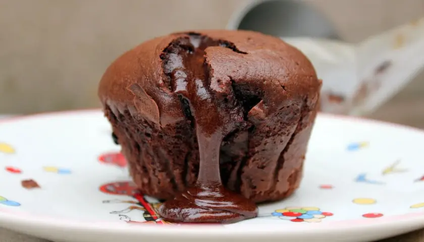 Coulant de chocolate con centro líquido y cremoso, servido en un plato decorado con globos.