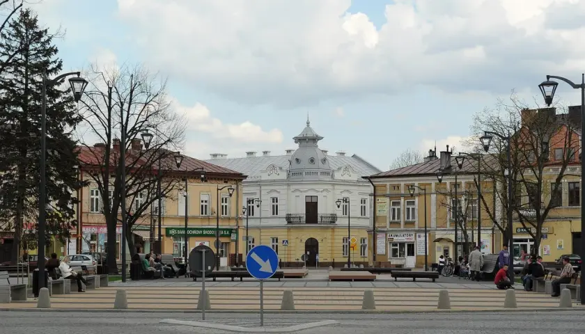 Rynek w Mielcu z kamienicami i ludźmi odpoczywającymi na ławkach. Idealne miejsce na mieleckie atrakcje na weekend.