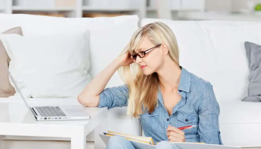 Junge Frau lernt am Laptop, ideal für online studium kostenlos. Sie sitzt auf dem Boden mit Büchern und Stift.