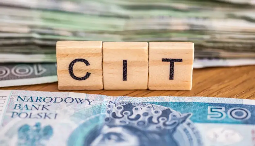 Drewniane klocki z literami "CIT" na tle polskich banknotów. Kluczowe dla dokumentacji cen transferowych.