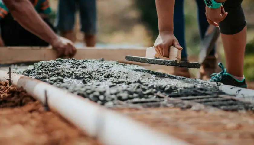 Pracownicy wygładzają świeży beton B25. Cena za m3 jest kluczowa przy planowaniu budowy.